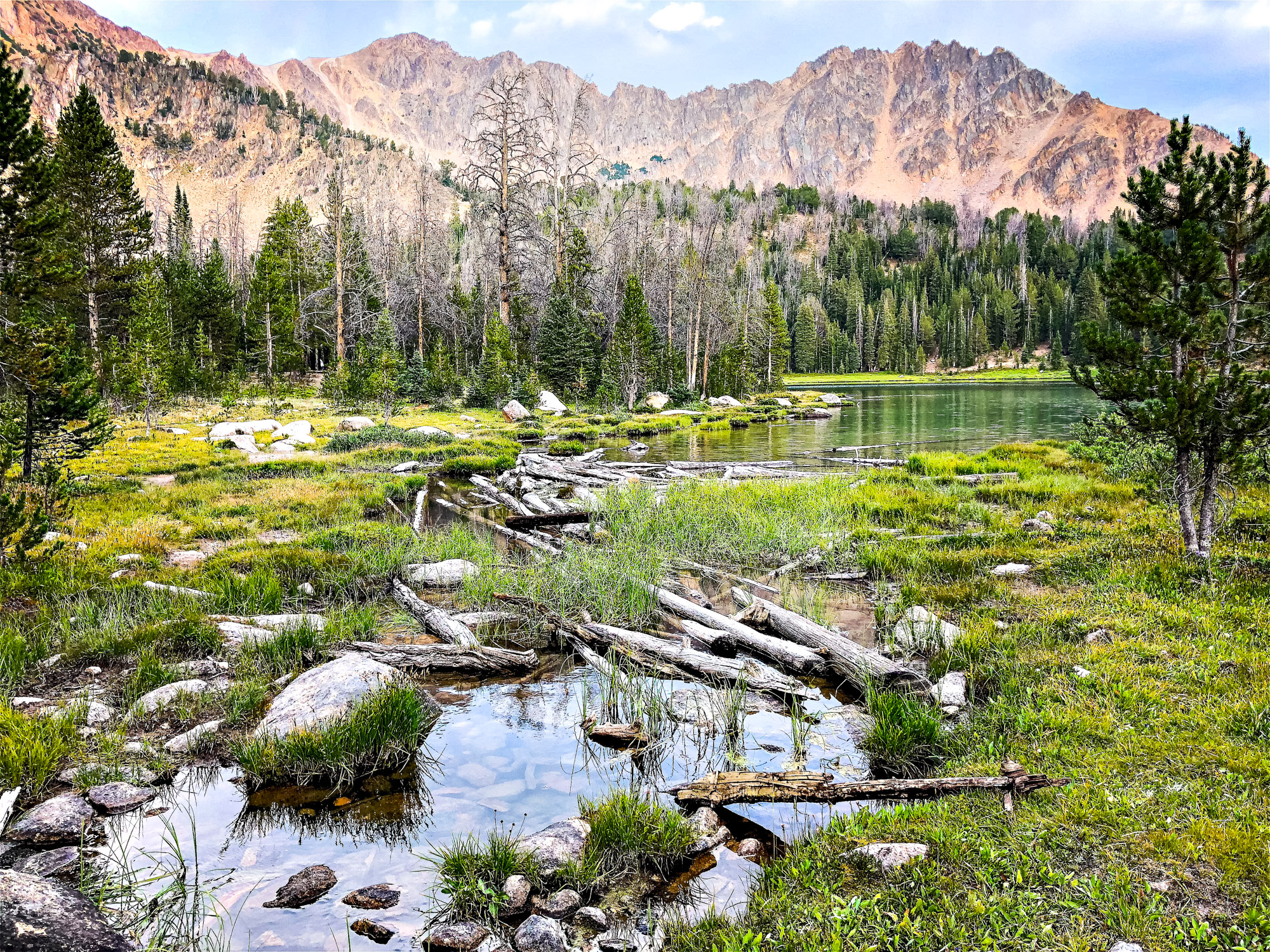 Hikes Near Stanley Idaho - a stream at the outlet of Fourth of July Lake in the White Cloud Wilderness. Sunset over the Chamberlain Lakes, seen from the edge of a high-elevation alpine lake near Castle Peak.
